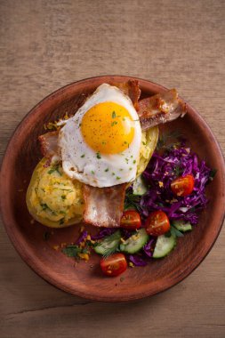 Fırında patates ceketli çedar peyniri ile yüklenen ve pastırma ile tepesinde ve ahşap masa tabakta Yumurta kızarmış. Tepegöz, dikey