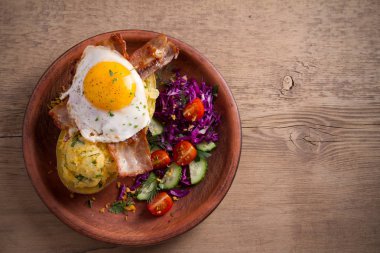 Fırında patates ceketli çedar peyniri ile yüklenen ve pastırma ile tepesinde ve ahşap masa tabakta Yumurta kızarmış. Tepegöz, yatay