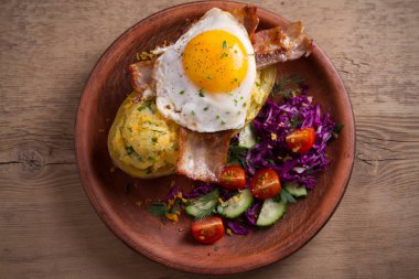 Fırında patates ceketli çedar peyniri ile yüklenen ve pastırma ile tepesinde ve ahşap masa tabakta Yumurta kızarmış. Tepegöz, yatay