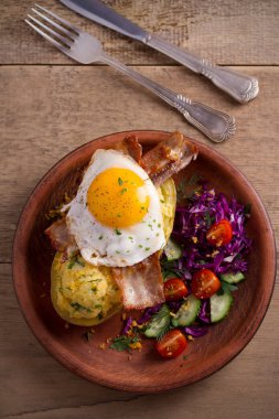 Fırında patates ceketli çedar peyniri ile yüklenen ve pastırma ile tepesinde ve ahşap masa tabakta Yumurta kızarmış. Tepegöz, dikey