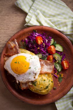 Fırında patates ceketli çedar peyniri ile yüklenen ve pastırma ile tepesinde ve ahşap masa tabakta Yumurta kızarmış. Tepegöz, dikey