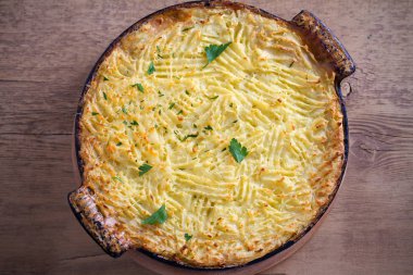 Klasik ev yapımı kıymalı börek (patates püresi ve sebzeli kıyma) tahta masada yemek pişirme güveç içinde. Tepegöz, yatay