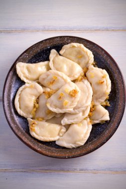 Pierogi veya pyrohy, varenyky, vareniki, köfte ahşap masa üzerinde kasede karamelize salamura soğan ile devam eder. dikey