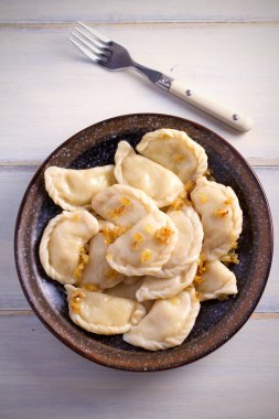 Pierogi veya pyrohy, varenyky, vareniki, köfte ahşap masa üzerinde kasede karamelize salamura soğan ile devam eder. dikey