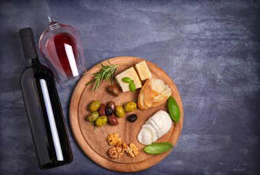 Şişe ve kadeh şarap ile peynir, zeytin, ekmek, fındık ve fesleğen koyu arka plan üzerinde. Yemek ve şarap kavramı. Yukarıdan görüntülemek, top