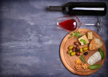 Şişe ve kadeh şarap ile peynir, zeytin, ekmek, fındık ve fesleğen koyu arka plan üzerinde. Yemek ve şarap kavramı. Yukarıdan görüntülemek, top