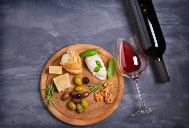 Şişe ve kadeh şarap ile peynir, zeytin, ekmek, fındık ve fesleğen koyu arka plan üzerinde. Yemek ve şarap kavramı. Yukarıdan görüntülemek, top
