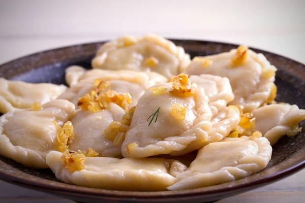 Pierogi veya pyrohy, varenyky, vareniki, köfte ahşap masa üzerinde kasede karamelize salamura soğan ile devam eder. Yatay