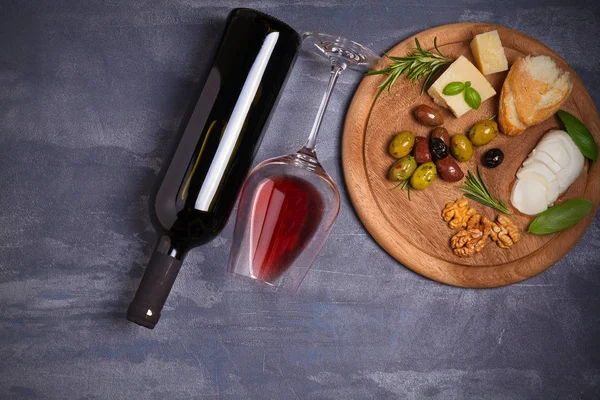 Şişe ve kadeh şarap ile peynir, zeytin, ekmek, fındık ve fesleğen koyu arka plan üzerinde. Yemek ve şarap kavramı. Yukarıdan görüntülemek, top