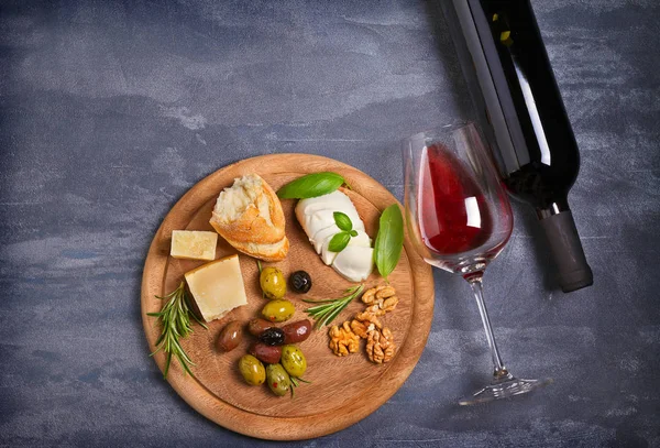 Şişe ve kadeh şarap ile peynir, zeytin, ekmek, fındık ve fesleğen koyu arka plan üzerinde. Yemek ve şarap kavramı. Yukarıdan görüntülemek, top