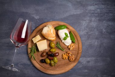 Bir kadeh şarap ile peynir, zeytin, ekmek, fındık ve fesleğen koyu arka plan üzerinde. Yemek ve şarap kavramı. Yukarıdan görüntülemek, top