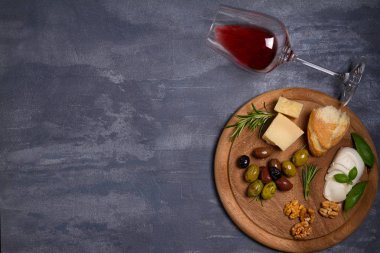 Bir kadeh şarap ile peynir, zeytin, ekmek, fındık ve fesleğen koyu arka plan üzerinde. Yemek ve şarap kavramı. Yukarıdan görüntülemek, top