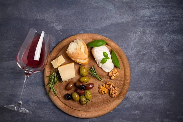 Bir kadeh şarap ile peynir, zeytin, ekmek, fındık ve fesleğen koyu arka plan üzerinde. Yemek ve şarap kavramı. Yukarıdan görüntülemek, top