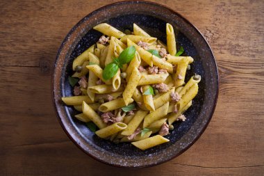 Ton balığı, fesleğen ve Kapari penne pesto sos kase ahşap arka plan ile. Ton balıklı makarna. Tepegöz, yatay