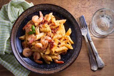 Karides penne güneş domates ve fesleğen kremsi mozzarella soslu kurutulmuş. Ahşap masa kase karides ile makarna. Tepegöz, yatay