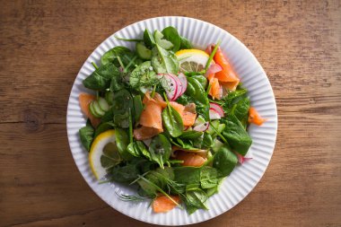 Füme somon ıspanak turp salatalık salatası ahşap masa üzerinde beyaz tabakta limonlu. Tepegöz, yatay