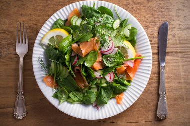 Füme somon ıspanak turp salatalık salatası ahşap masa üzerinde beyaz tabakta limonlu. Tepegöz, yatay