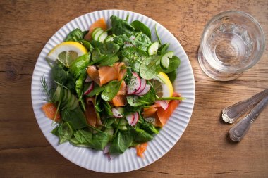 Füme somon ıspanak turp salatalık salatası ahşap masa üzerinde beyaz tabakta limonlu. Tepegöz, yatay