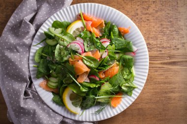 Füme somon ıspanak turp salatalık salatası ahşap masa üzerinde beyaz tabakta limonlu. Tepegöz, yatay