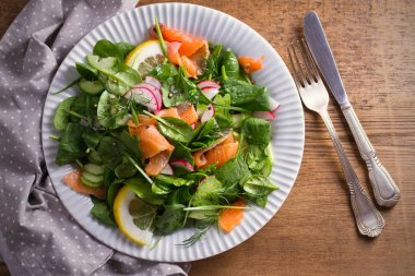 Füme somon ıspanak turp salatalık salatası ahşap masa üzerinde beyaz tabakta limonlu. Tepegöz, yatay