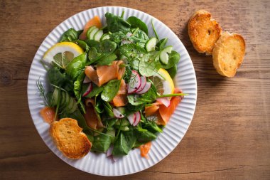 Füme somon ıspanak turp salatalık salatası ahşap masa üzerinde beyaz tabakta limonlu. Tepegöz, yatay