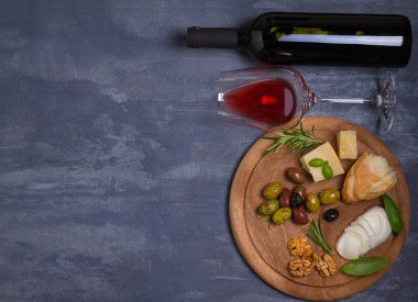 Şişe ve kadeh şarap ile peynir, zeytin, ekmek, fındık ve biberiye koyu arka plan üzerinde. Yemek ve şarap kavramı, banner. Tepegöz, yatay