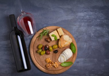 Şişe ve kadeh şarap ile peynir, zeytin, ekmek, fındık ve biberiye koyu arka plan üzerinde. Yemek ve şarap kavramı, banner. Tepegöz, yatay