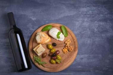 Şişe ve kadeh şarap ile peynir, zeytin, ekmek, fındık ve biberiye koyu arka plan üzerinde. Yemek ve şarap kavramı, banner. Tepegöz, yatay