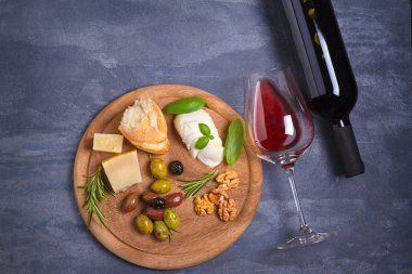 Şişe ve kadeh şarap ile peynir, zeytin, ekmek, fındık ve biberiye koyu arka plan üzerinde. Yemek ve şarap kavramı, banner. Tepegöz, yatay