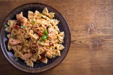 Makarna tavukla, domates ve fesleğen ahşap masa üzerinde bir kapta krem mozzarella soslu kurutulmuş. Tepegöz, yatay 