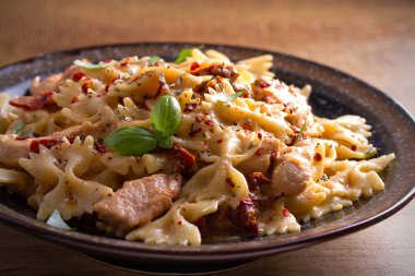 Makarna tavukla, domates ve fesleğen ahşap masa üzerinde bir kapta krem mozzarella soslu kurutulmuş. Yatay 