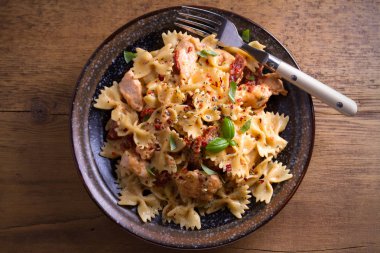 Makarna tavukla, domates ve fesleğen ahşap masa üzerinde bir kapta krem mozzarella soslu kurutulmuş. Tepegöz, yatay 