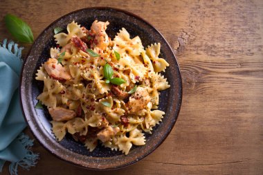 Makarna tavukla, domates ve fesleğen ahşap masa üzerinde bir kapta krem mozzarella soslu kurutulmuş. Tepegöz, yatay 