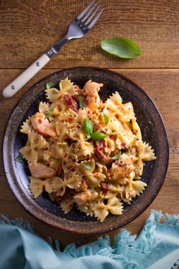 Makarna tavukla, domates ve fesleğen ahşap masa üzerinde bir kapta krem mozzarella soslu kurutulmuş. Tepegöz, dikey 