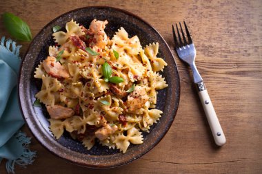 Makarna tavukla, domates ve fesleğen ahşap masa üzerinde bir kapta krem mozzarella soslu kurutulmuş. Tepegöz, yatay 