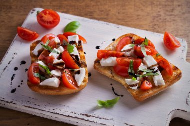 Caprese Bruschetta beyaz rustik doğrama tahtası üzerinde. Domates, fesleğen, mozzarella peyniri tost balsamik soslu. Meze - starter çanak. Yatay