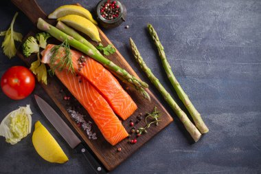 Taze çiğ somon bifteği, sebzeler ve pişirmek için malzemelerle birlikte. Yatay görüntünün üstünde