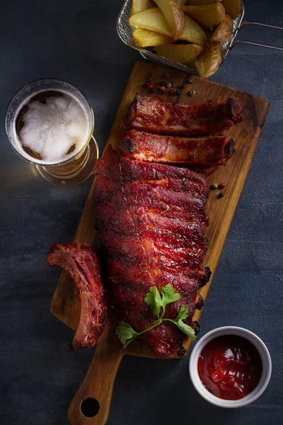 Rack of ribs, barbecue sauce, fries and light beer. Overhead vertical image