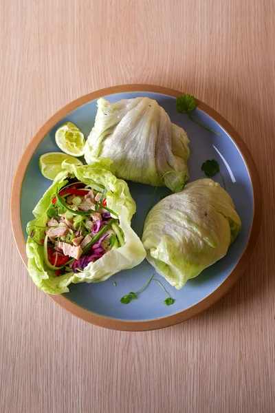 Stuffed iceberg lettuce leaves with turkey and vegetables on blue plate. Healthy diet food. Overhead image