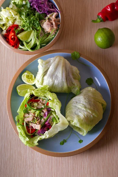Stuffed iceberg lettuce leaves with turkey and vegetables on blue plate. Healthy diet food. Overhead image