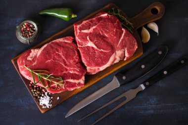 Raw fresh meat, beef steak fillet on wood chopping board, dark background. Overhead, flat lay image