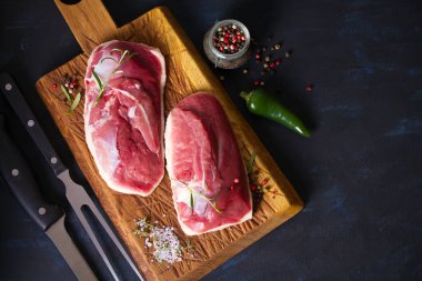 Çiğ taze et, ahşap doğrama tahtasındaki ördek göğsü filetosu biberiye ve mevsimlerle birlikte. Düz yatıyordu