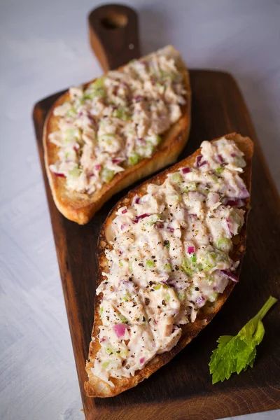 Tuna salad sandwiches on chopping board, white background. Vertical image