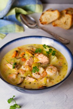 Beyaz arka planda somon balıklı deniz ürünleri çorbası.