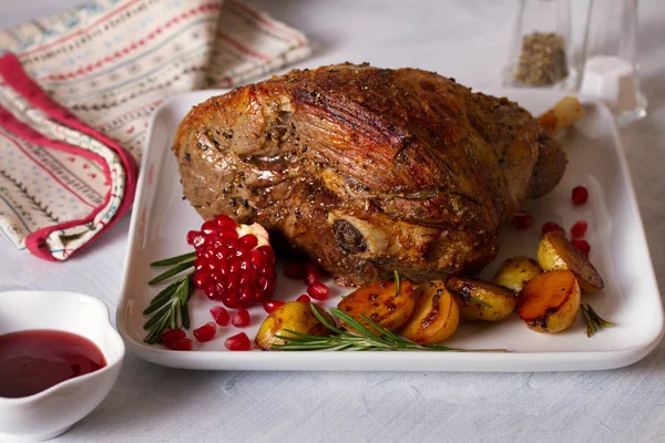 Roast leg of lamb with potatoes, pomegranate and rosemary