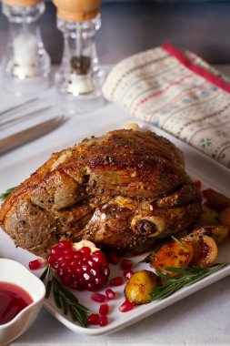 Beyaz tabakta patates, nar tohumu ve biberiye ile servis edilen kuzu budu, dikey görüntü
