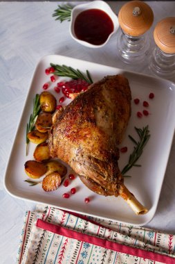 Patates, nar tohumu ve beyaz tabakta biberiye ile servis edilen kuzu budu manzarası.