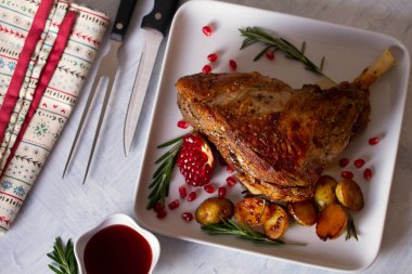Patates, nar tohumu ve beyaz tabakta biberiye ile servis edilen kuzu budu manzarası.