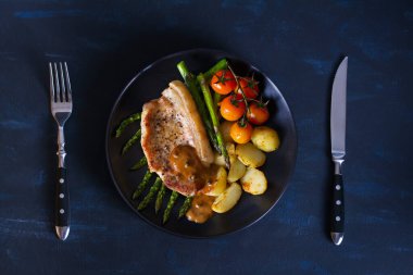 Biber soslu domuz pirzolası, kuşkonmaz, patates ve domates. Yukarıdan görüntüle, en üstten