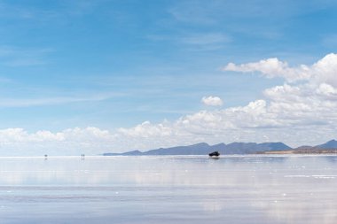 Bolivya 'daki Salar de Uyuni' de su ile kaplı araba ve bulutların yansımaları